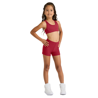 girl facing front with hand on hips wearing a red sports bra and red compression shorts