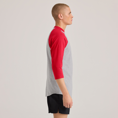 man facing side wearing a grey and red baseball t shirt and black shorts 210M