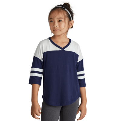 girl facing front wearing a navy blue and white striped v neck t shirt and grey pants
