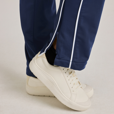woman facing side wearing royal blue warm up pants with white piping on the legs 3245V closeup