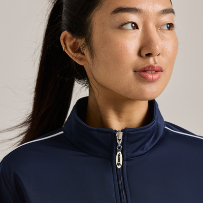 woman angled front wearing a navy zip up warm up jacket and white piping on the sleeves 3265V closeup