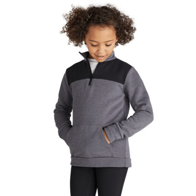 girl facing front looking down wearing a grey and black colorblocked quarter zip sweatshirt with hands in front pocket