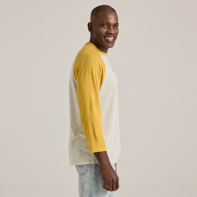 man facing side wearing Delta Platinum Men's Tri-Blend 3/4 Sleeve Raglan wholesale blank Tee white body yellow sleeves
